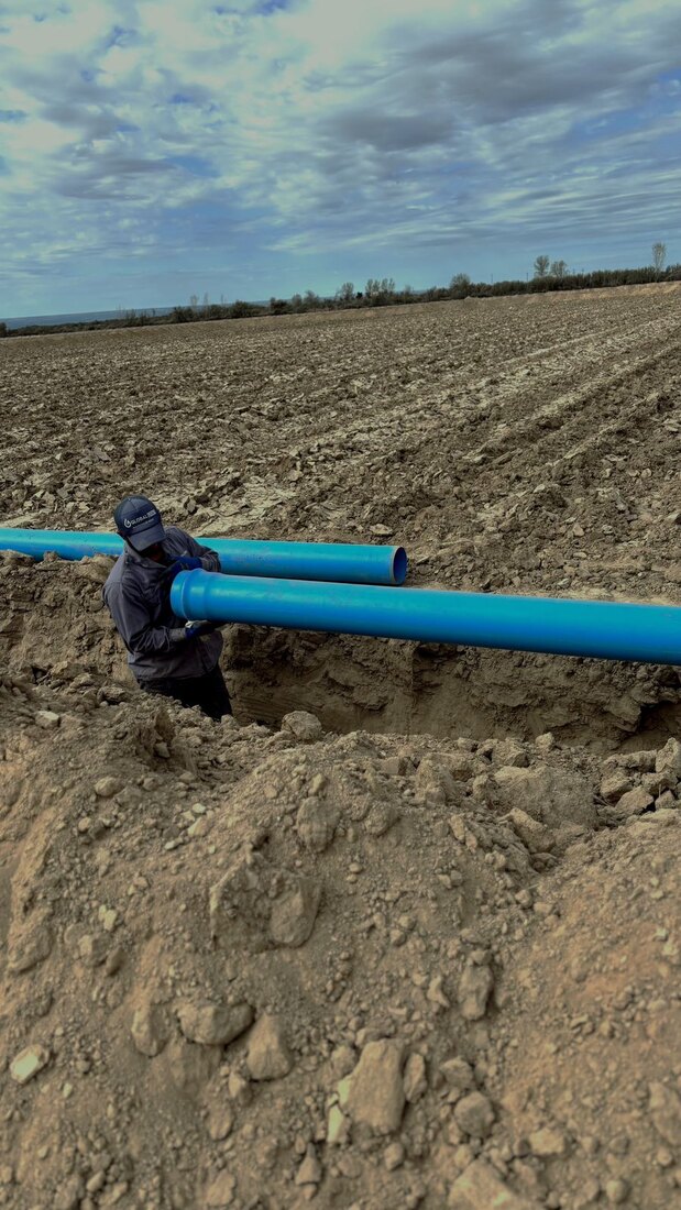 Operario tendiendo caños de PVC en el campo